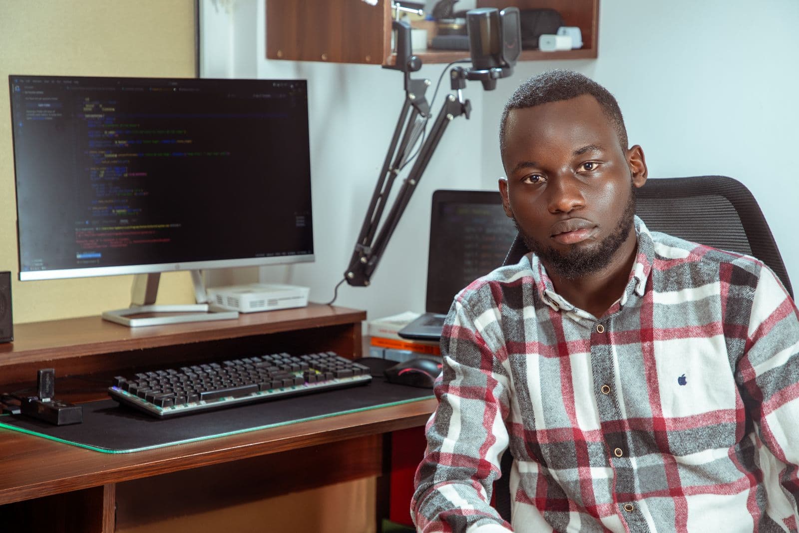 Software developer at his workstation with a code editor open on the monitor beside him